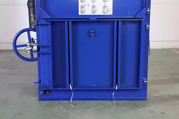 Bottom view of the lower half of the blue BP3CD baler. The lower door is closed and two pieces of tape are threaded through the lengthways slats in the middle of the door.
