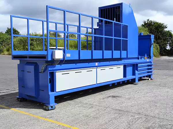 Side view of the CB58 baler in blue with a walk-on platform. The machine stands outside.