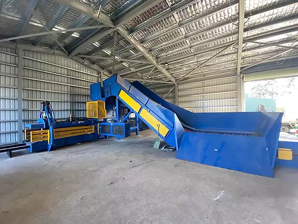 Wide shot of the CB-S Channel Baler positioned in the corner of a large warehouse.