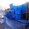 Large blue machine outside with bales of compacted plastic surrounding it.