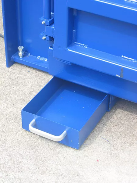 A blue drawer with a silver handle is pulled out of the bottom of a machine.