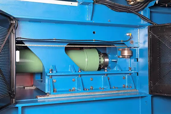 Close-up view of the green hydraulic cylinder in the blue Twin Ram Baler.