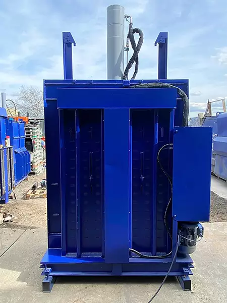 The PP1207 baler in blue with its back side opened, revealing a hollow chamber with a few wires.